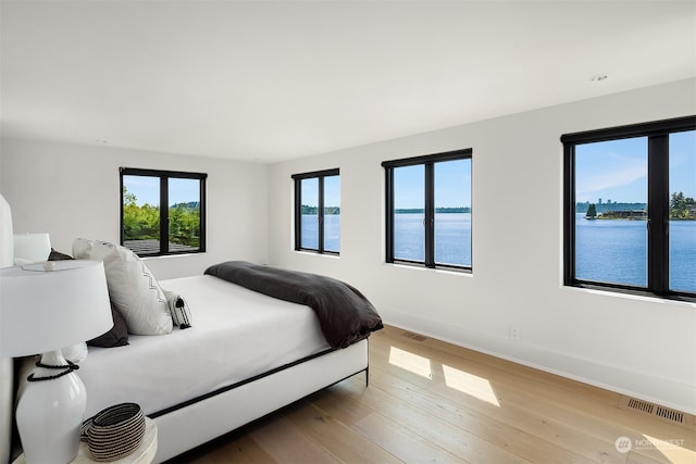 bedroom featuring a water view and wood-type flooring