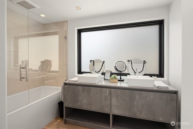 bathroom with hardwood / wood-style flooring, combined bath / shower with glass door, and vanity