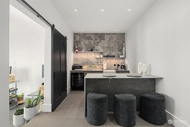 bar featuring a barn door, wine cooler, tasteful backsplash, and light tile patterned flooring