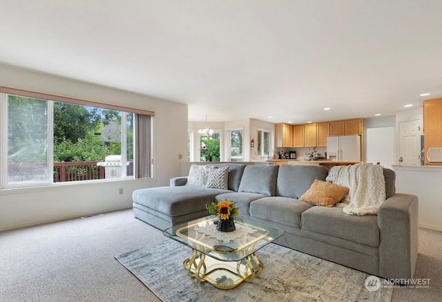 carpeted living room with a chandelier