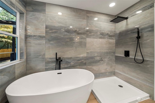 full bathroom featuring a freestanding bath, tile walls, and tiled shower