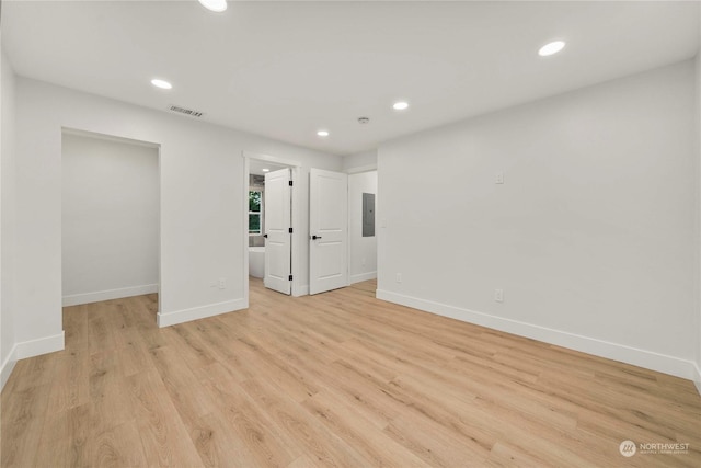 unfurnished room with light wood-style flooring, electric panel, baseboards, and recessed lighting