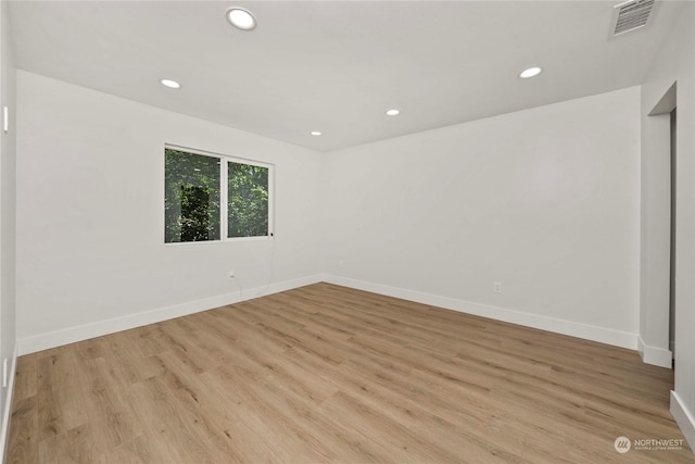 unfurnished room with baseboards, light wood-type flooring, visible vents, and recessed lighting