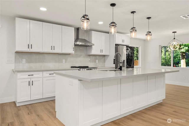 kitchen featuring wall chimney exhaust hood, backsplash, a sink, and light countertops