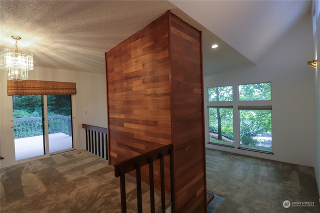 interior space with lofted ceiling, a chandelier, dark colored carpet, and a textured ceiling