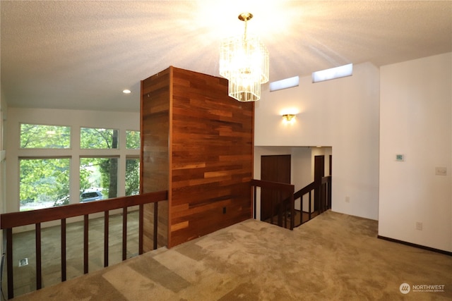 interior space featuring a textured ceiling, a notable chandelier, and carpet floors