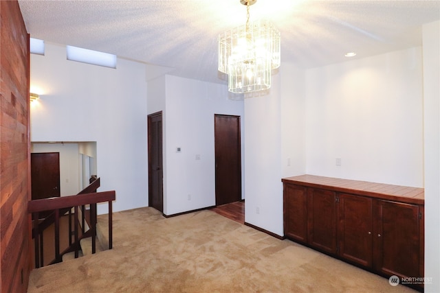 interior space with a textured ceiling, an inviting chandelier, and light colored carpet