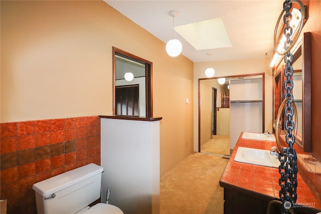 bathroom with vanity, toilet, a skylight, and a textured ceiling