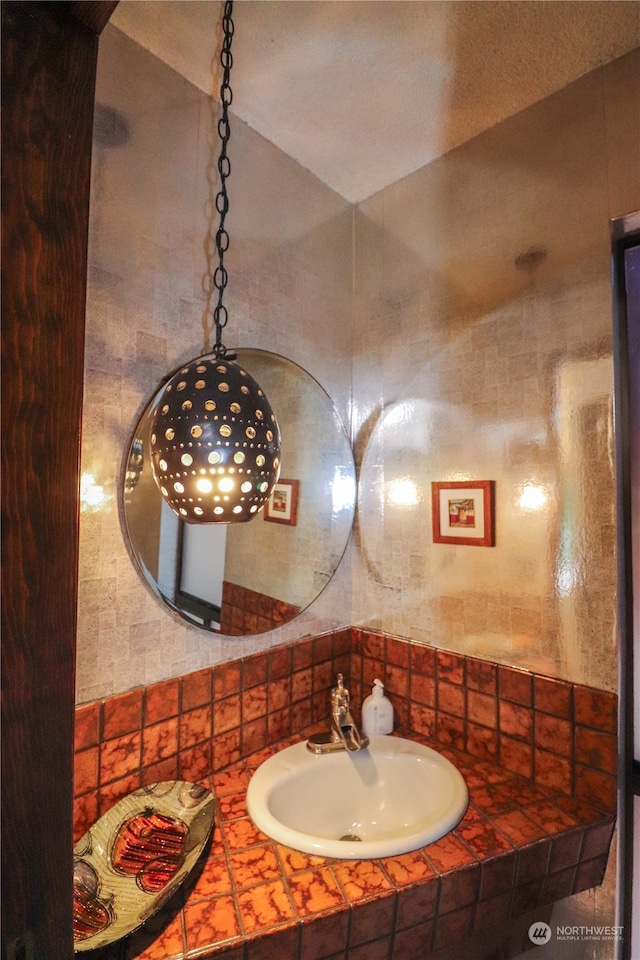 bathroom with vaulted ceiling, tasteful backsplash, and sink