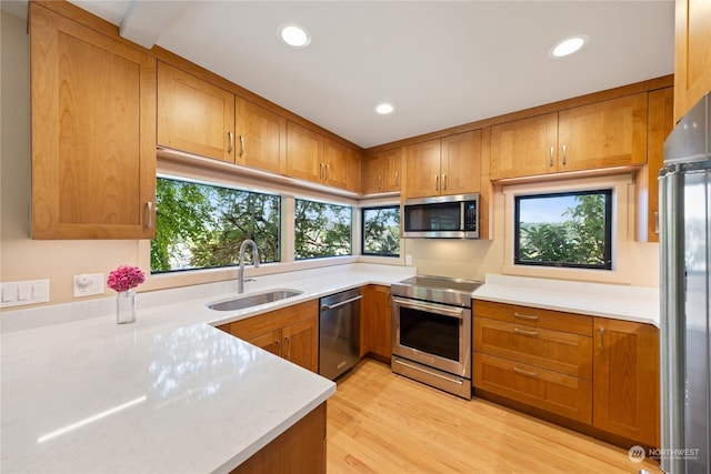 kitchen featuring plenty of natural light, light hardwood / wood-style floors, appliances with stainless steel finishes, and beam ceiling