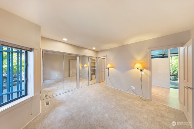 unfurnished bedroom featuring a closet, light colored carpet, and multiple windows