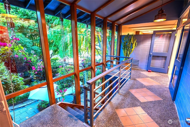 unfurnished sunroom featuring lofted ceiling with beams