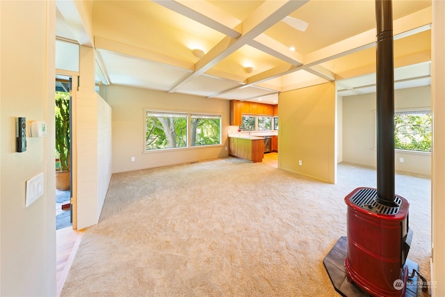 interior space featuring coffered ceiling, beam ceiling, and a wood stove