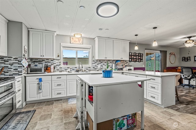 kitchen with a kitchen island, a peninsula, light countertops, double oven range, and a sink