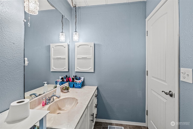 bathroom with vanity, baseboards, and a textured wall