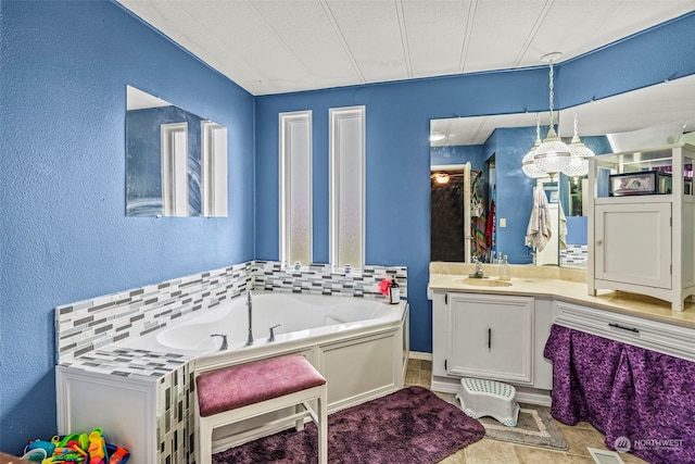 bathroom with a textured wall, vanity, and a bath