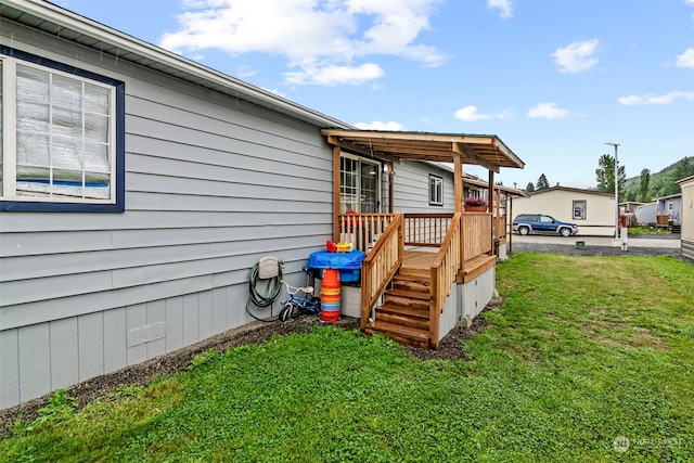 view of side of property with a deck and a lawn