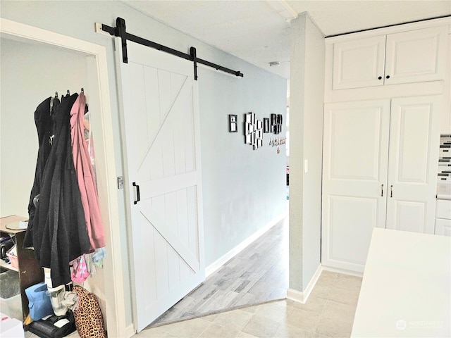 hall with light tile patterned floors, a barn door, and baseboards