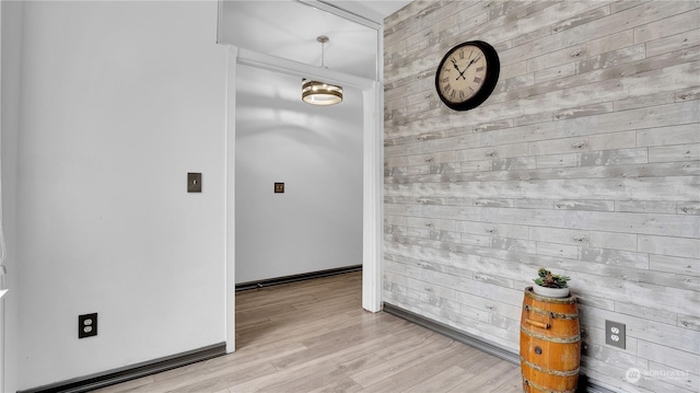 spare room featuring wooden walls, light wood-style floors, and baseboards