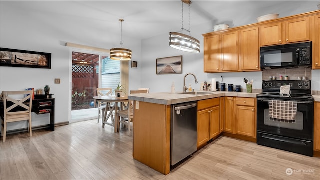 kitchen with light wood-type flooring, sink, black appliances, kitchen peninsula, and pendant lighting