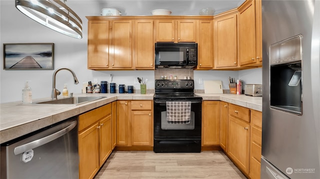 kitchen with black appliances, tile countertops, light hardwood / wood-style flooring, and sink