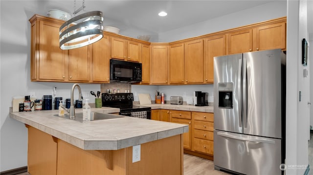 kitchen with a kitchen breakfast bar, black appliances, light hardwood / wood-style flooring, kitchen peninsula, and sink