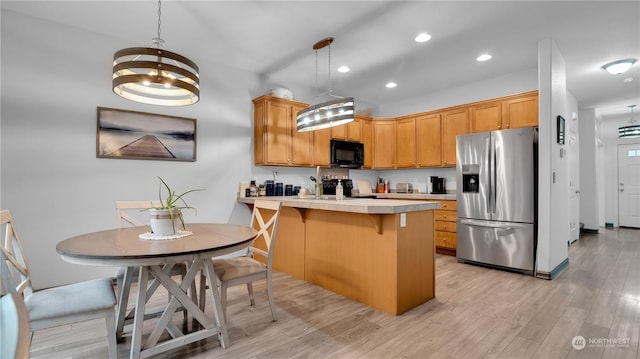 kitchen with black microwave, light countertops, a peninsula, light wood-style floors, and stainless steel refrigerator with ice dispenser
