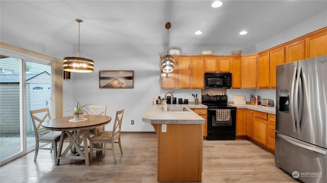 kitchen with recessed lighting, a peninsula, light wood-style floors, black appliances, and a sink