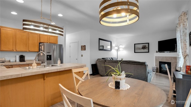 dining room featuring recessed lighting, light wood-style flooring, and a tiled fireplace