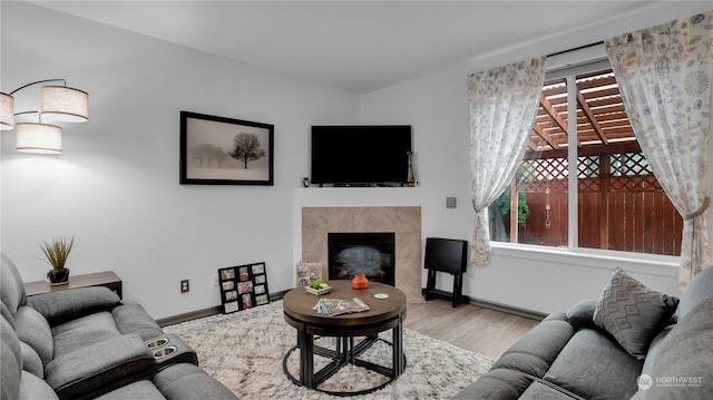living area with a tiled fireplace, baseboards, and wood finished floors