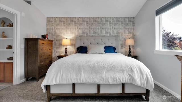 bedroom with carpet flooring, an accent wall, and baseboards