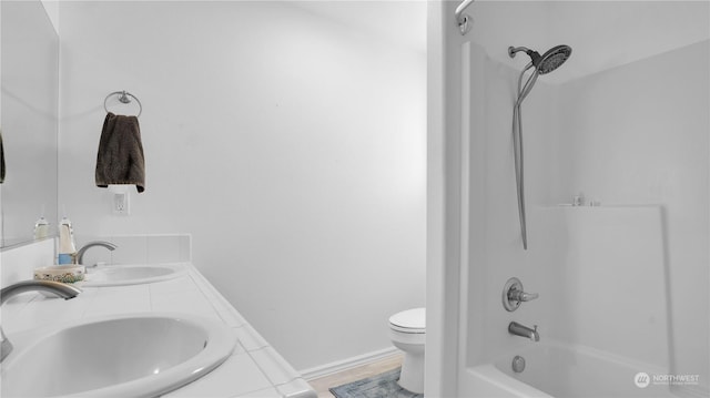 bathroom featuring double vanity, toilet, shower / tub combination, and a sink