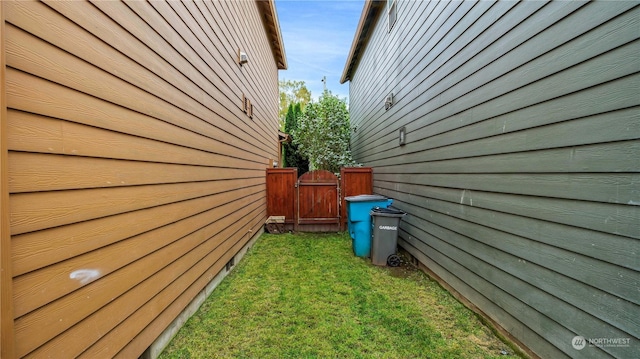 view of home's exterior with a yard and a gate