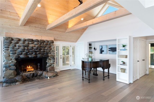 living room with high vaulted ceiling, wood-type flooring, beam ceiling, and a stone fireplace