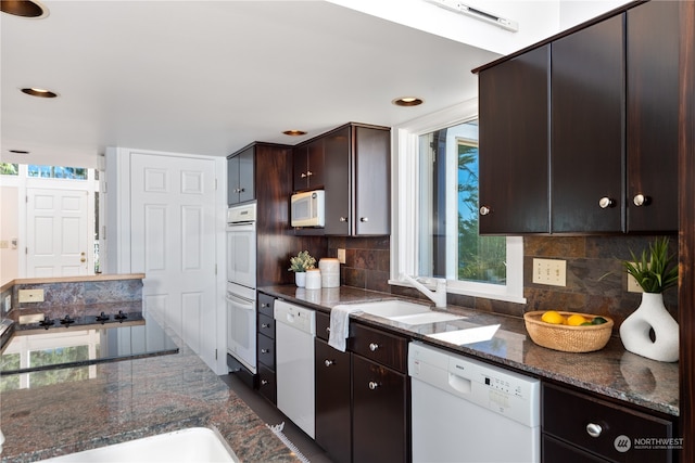 kitchen featuring white appliances, a wealth of natural light, dark brown cabinets, and decorative backsplash