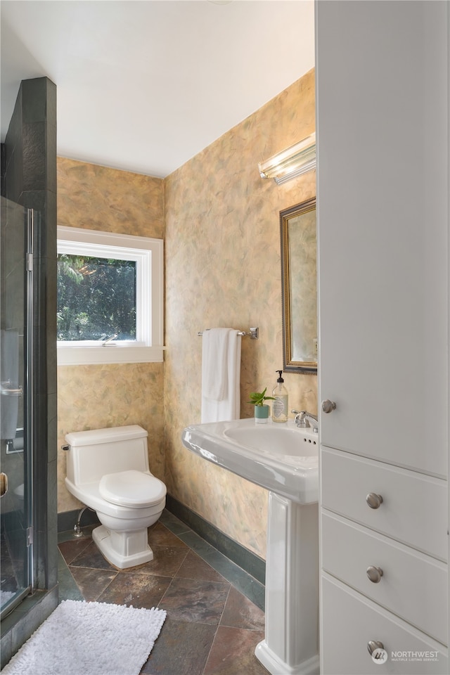 bathroom featuring a shower with shower door and toilet