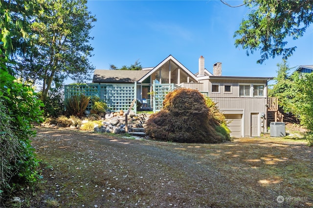 back of house with a garage and central AC unit