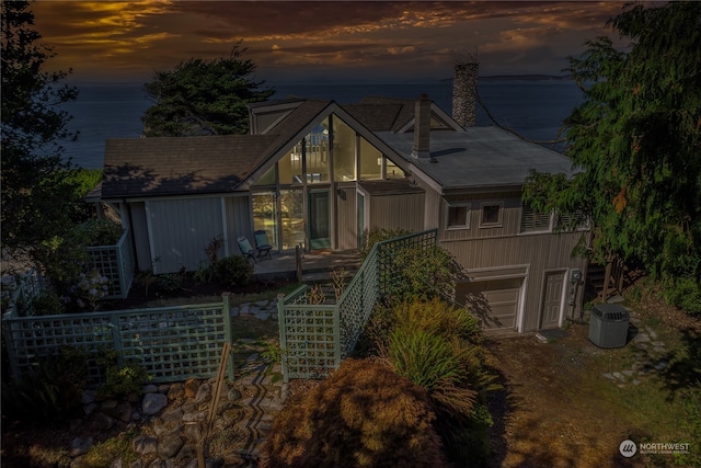 view of front facade with a garage, a water view, and central air condition unit