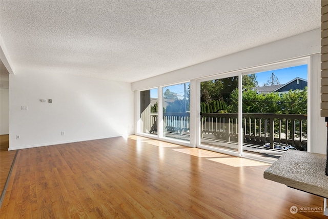 unfurnished living room with hardwood / wood-style floors, plenty of natural light, and a textured ceiling