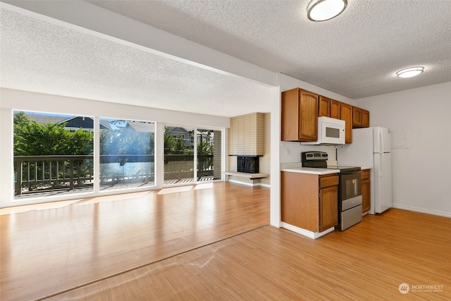 kitchen with light wood-type flooring, white appliances, a healthy amount of sunlight, and a textured ceiling