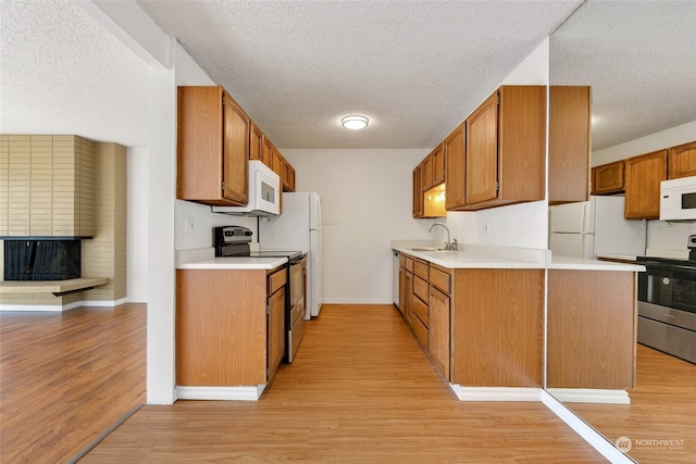 kitchen with white appliances, light hardwood / wood-style flooring, sink, and a textured ceiling