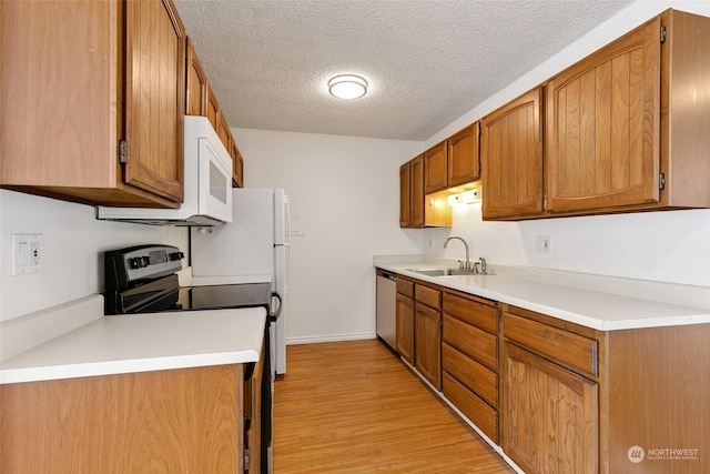 kitchen featuring appliances with stainless steel finishes, a textured ceiling, sink, and light hardwood / wood-style floors