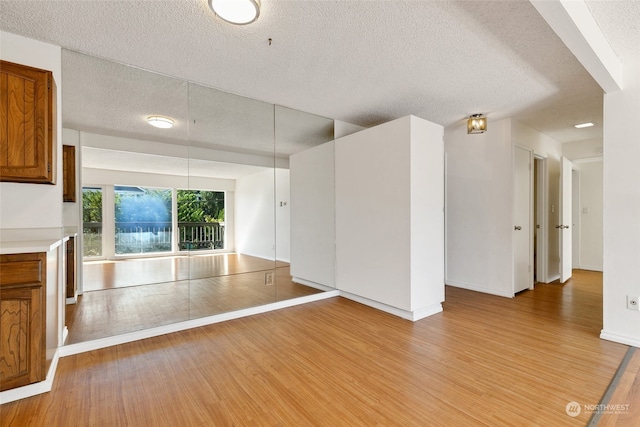 unfurnished living room with light wood-type flooring and a textured ceiling