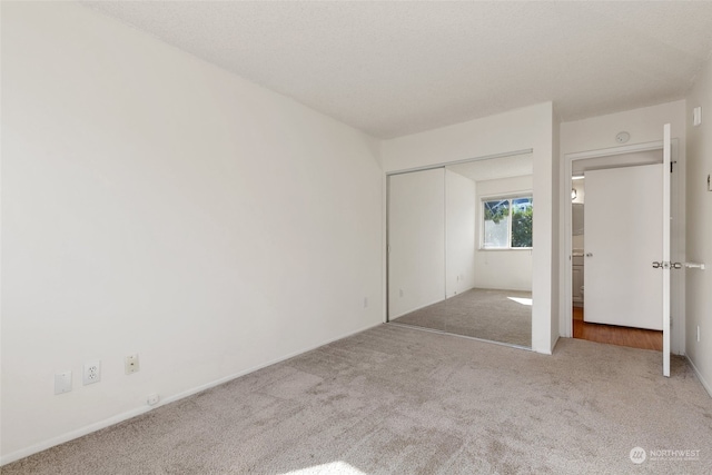 unfurnished bedroom featuring light carpet and a closet