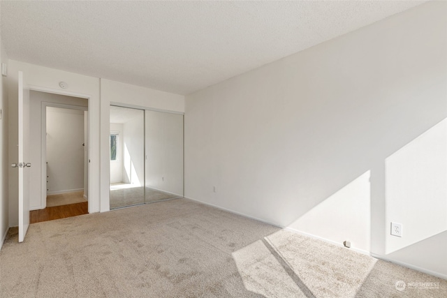 unfurnished bedroom with light carpet, a textured ceiling, and a closet