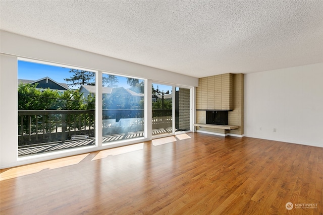 unfurnished living room with a fireplace, a textured ceiling, and hardwood / wood-style floors