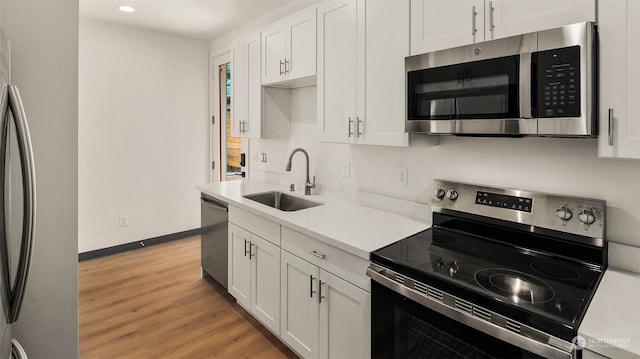 kitchen with stainless steel appliances, light hardwood / wood-style floors, white cabinetry, and sink