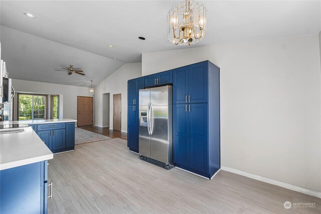 kitchen with light wood-style flooring, blue cabinets, vaulted ceiling, light countertops, and stainless steel refrigerator with ice dispenser