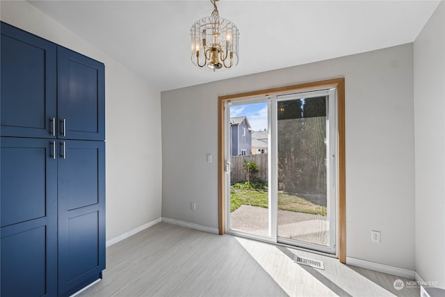 unfurnished bedroom with light hardwood / wood-style floors, an inviting chandelier, and access to exterior