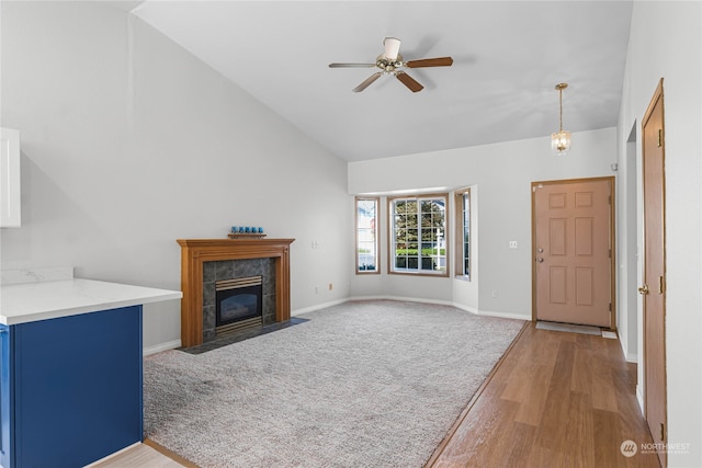 unfurnished living room featuring ceiling fan, a fireplace, vaulted ceiling, and light hardwood / wood-style flooring